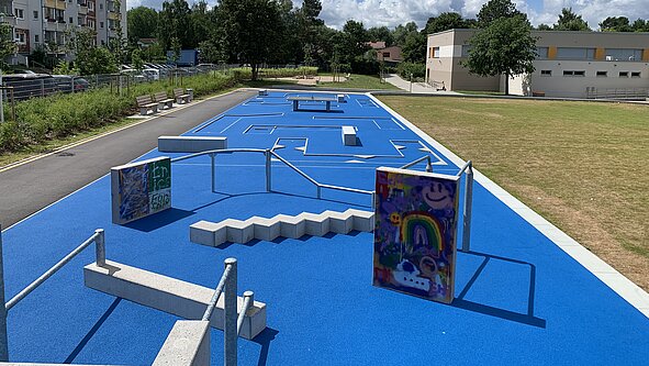 Fitnessparcours mit blauen Trainingsstationen im Freien unter bewölktem Himmel