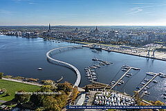 Gebogene Warnowbrücke bei Gehlsdorf über den Fluss mit Blick auf Rostock und Hafenanlagen im Hintergrund