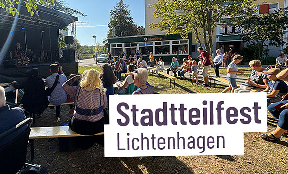 Menschen versammeln sich bei einem Stadtteilfest in Lichtenhagen mit einem Banner 'Stadtteilfest Lichtenhagen'