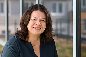 Frau mit dunklen schulterlangen Haaren lächelt in die Kamera.