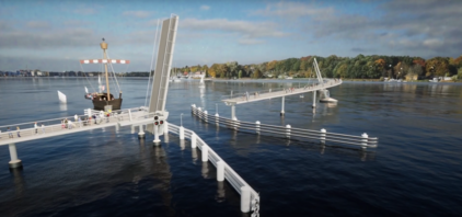 Geöffnete Klappbrücke über einen Fluss mit Segelbooten und einem Schiff im Hintergrund, herbstliche Bäume am Ufer
