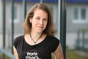 Porträt einer Frau mit lockigem, braunem Haar.