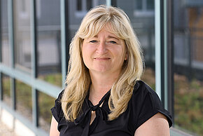 Frau mit blonden Haaren und neutralem Gesichtsausdruck.