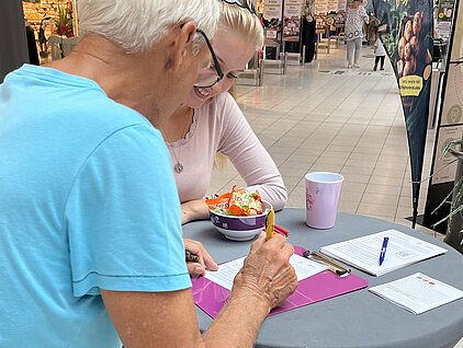 Älterer Herr lässt sich Fragebogen am RGS-Stand  erklären.