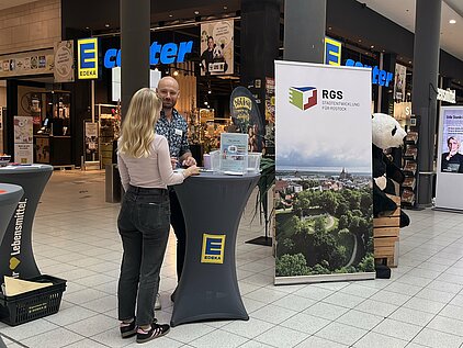 Zwei Personen stehen am RGS-Stand im Warnowpark Lütten Klein und unterhalten sich.